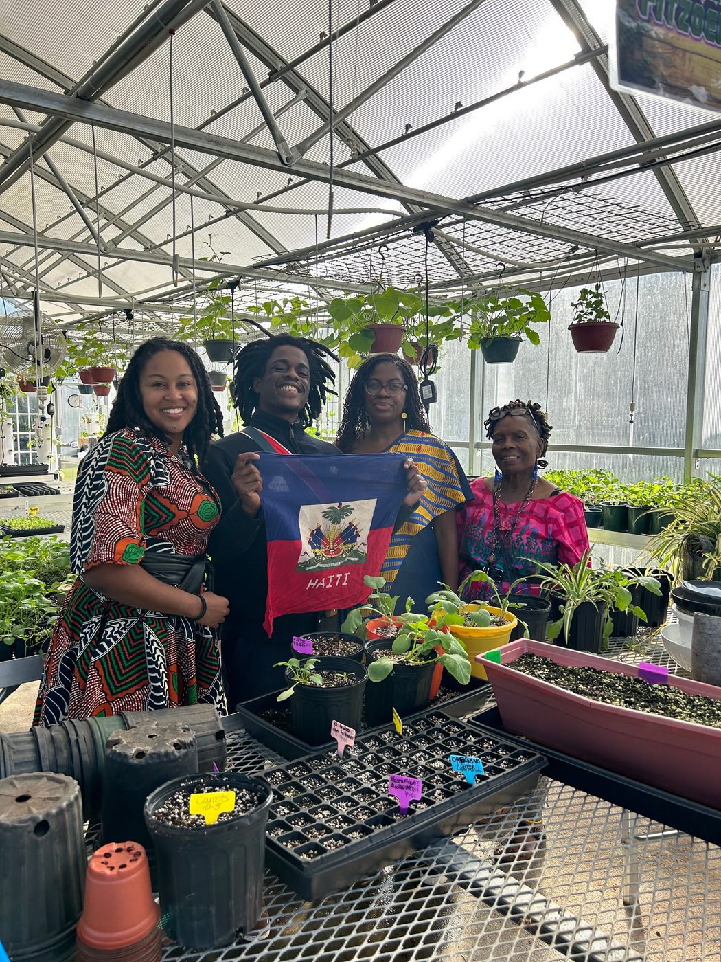 SEAUX9 holding the Haitian flag in a greenhouse