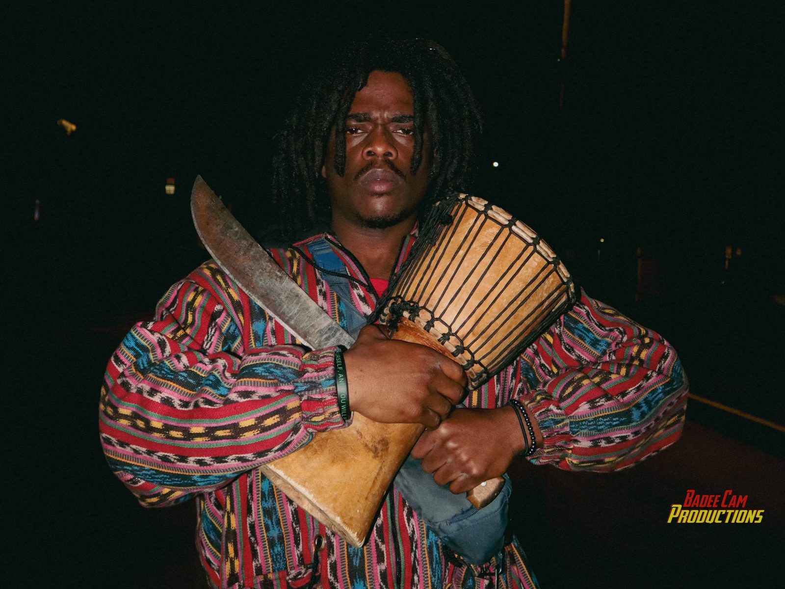 SEAUX9 holding a djembe drum and machete